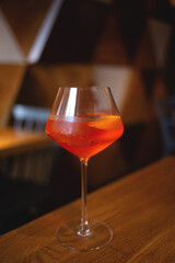 A refreshing orange cocktail in a wine glass on a wooden table, perfect for a relaxing evening