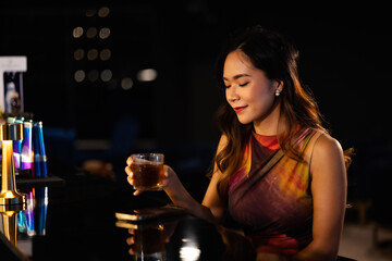 A woman drinks alcohol and gets drunk at a bar at night.