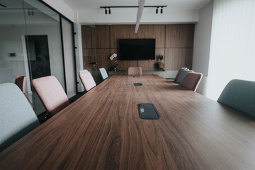 A spacious and stylish office conference room featuring sleek wooden table and contemporary chairs. Ideal for business meetings and team collaborations.