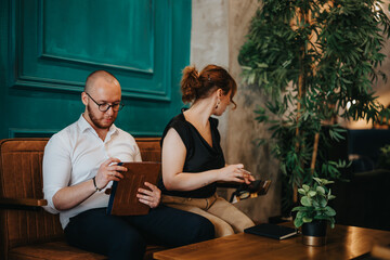 Obraz premium Business colleagues collaborating in a contemporary office space, focusing on tasks with digital devices and notebooks. Professional setting with a friendly and productive atmosphere.