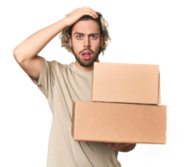 Young man with cardboard boxes in studio being shocked, she has remembered important meeting.