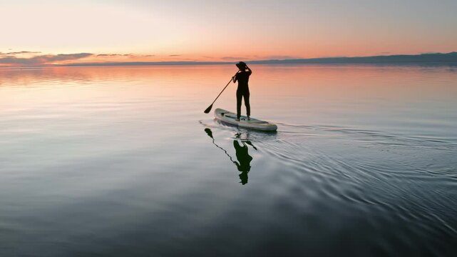Young sporty lady walks on standup paddle sup board at sunset calm lake. Active vacations concept