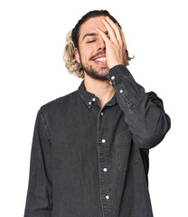 Young Caucasian man in studio setting laughing happy, carefree, natural emotion.