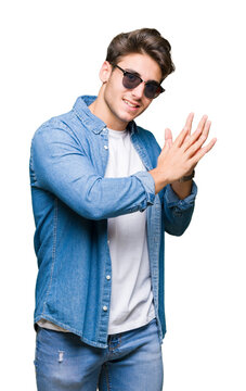 Young handsome man wearing sunglasses over isolated background Clapping and applauding happy and joyful, smiling proud hands together