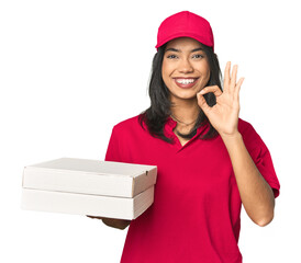 Latina delivering pizza, studio setup cheerful and confident showing ok gesture.