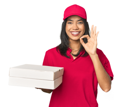 Latina delivering pizza, studio setup cheerful and confident showing ok gesture.