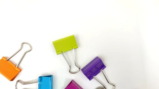Top view of colorful binder clips, isolated on white background.