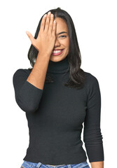 Simple portrait of a young Latina having fun covering half of face with palm.