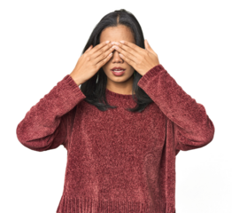 Simple portrait of a young Latina afraid covering eyes with hands.