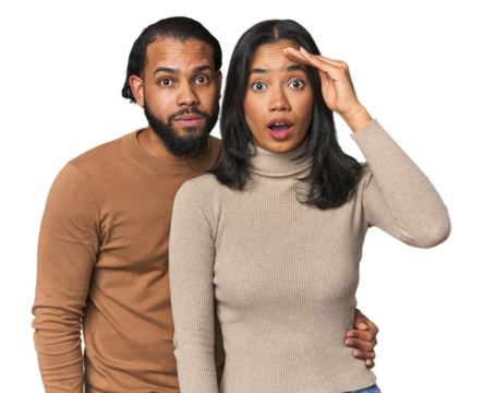 Young Latino couple in studio shouts loud, keeps eyes opened and hands tense.