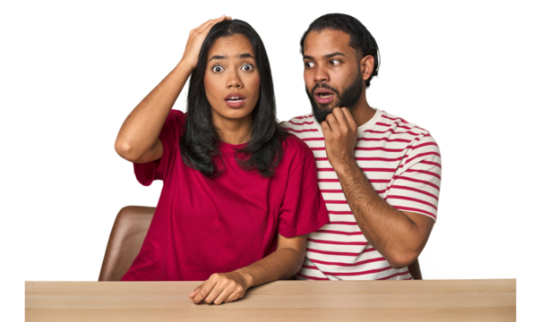 Seated young Latino couple at table being shocked, she has remembered important meeting.