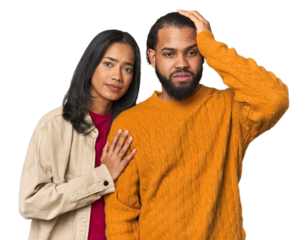 Young Latino couple in studio tired and very sleepy keeping hand on head.