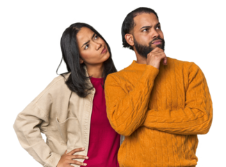 Young Latino couple in studio thinking and looking up, being reflective, contemplating, having a fantasy.