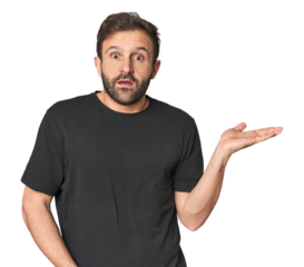 Studio portrait of young Hispanic male impressed holding copy space on palm.