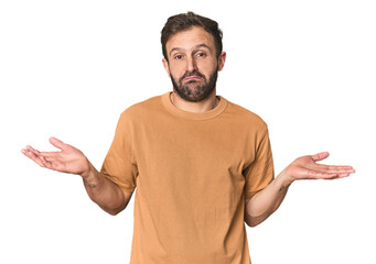 Studio portrait of young Hispanic male doubting and shrugging shoulders in questioning gesture.