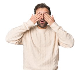 Studio portrait of young Hispanic male afraid covering eyes with hands.