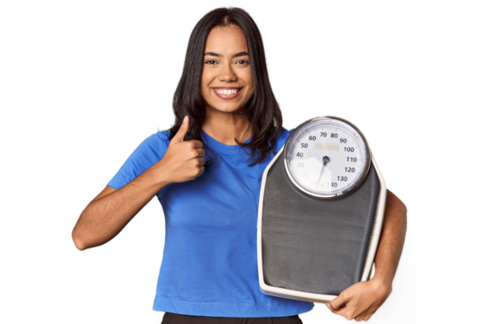 Filipino woman with scale in studio smiling and raising thumb up