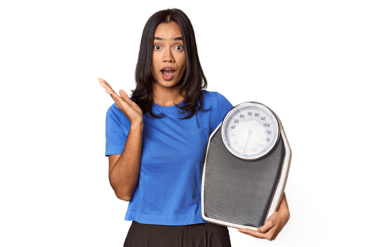 Filipino woman with scale in studio surprised and shocked. - Powered by Adobe
