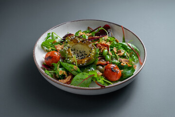 Fresh salad with beet greens, arugula, avocado, tomato, beans and sesame seeds