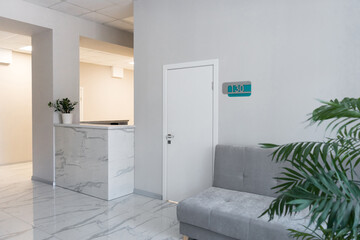Hall in clinic with modern interior, comfortable couch and reception desk