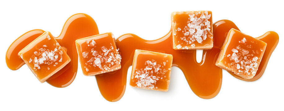 Five salty or salted caramel candy cubes topped with caramel sauce and sea salt on white background - Powered by Adobe
