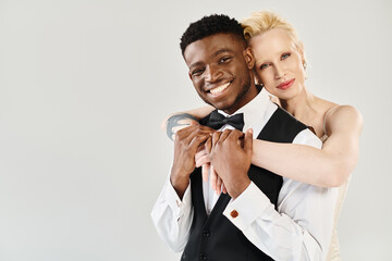 A stylish man in a tuxedo tenderly embraces a woman in a classy black and white dress. Love and sophistication are in the air.