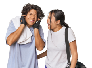 Young interracial athletic couple in studio covering ears with hands.
