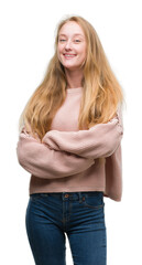 Blonde teenager woman wearing pink sweater happy face smiling with crossed arms looking at the camera. Positive person.