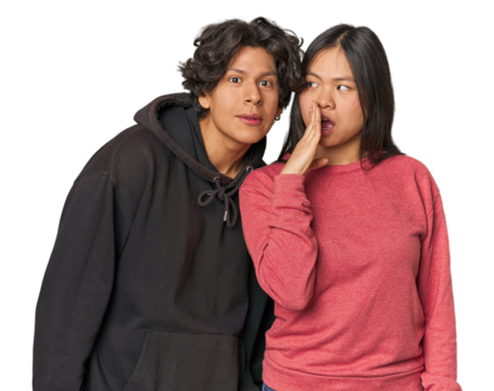 Young interracial couple in studio is saying a secret hot braking news and looking aside - Powered by Adobe