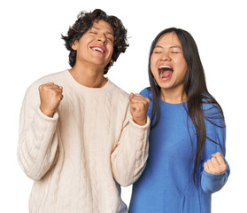 Young interracial couple in studio celebrating a victory, passion and enthusiasm, happy expression.