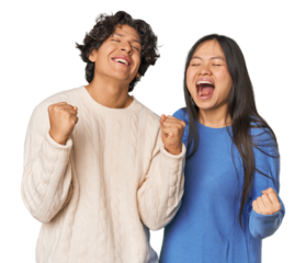 Young interracial couple in studio celebrating a victory, passion and enthusiasm, happy expression.