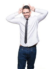 Fototapeta premium Young handsome business man wearing glasses over isolated background Posing funny and crazy with fingers on head as bunny ears, smiling cheerful