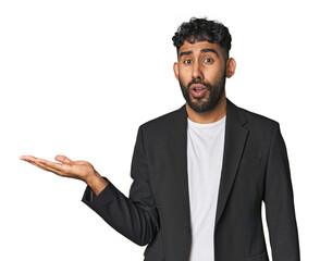 Hispanic businessman in suit in studio impressed holding copy space on palm.