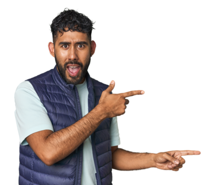 Young Hispanic man isolated shocked pointing with index fingers to a copy space.