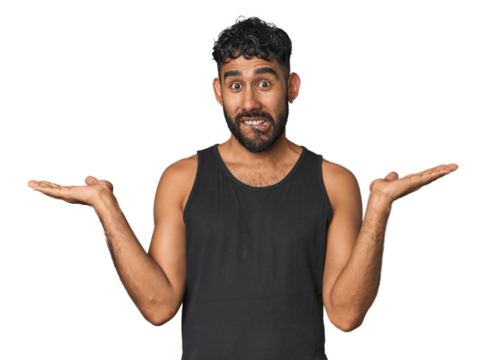 Young Hispanic man isolated confused and doubtful shrugging shoulders to hold a copy space.