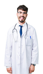 Fototapeta premium Young doctor man wearing hospital coat over isolated background sticking tongue out happy with funny expression. Emotion concept.