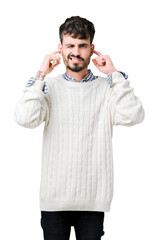 Naklejka premium Young handsome man wearing winter sweater over isolated background covering ears with fingers with annoyed expression for the noise of loud music. Deaf concept.