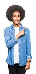 Young african american man with afro hair cheerful with a smile of face pointing with hand and finger up to the side with happy and natural expression on face