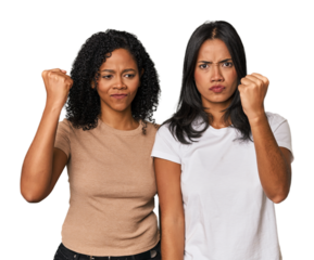 Young Latin friends in studio showing fist to camera, aggressive facial expression.