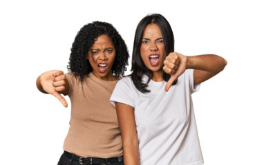 Young Latin friends in studio showing thumb down and expressing dislike.