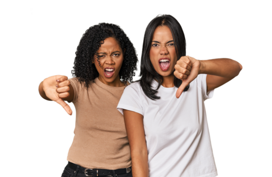 Young Latin friends in studio showing thumb down and expressing dislike.