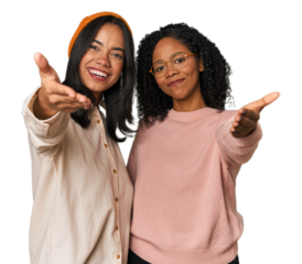 Young Latin friends together in studio stretching hand at camera in greeting gesture.