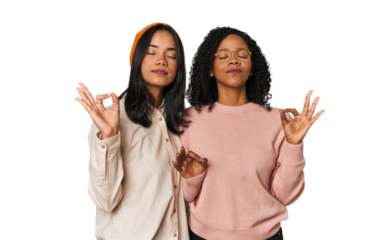 Young Latin friends together in studio relaxes after hard working day, she is performing yoga.