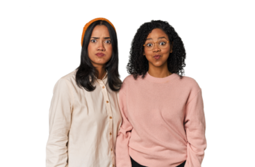 Young Latin friends together in studio blows cheeks, has tired expression. Facial expression concept.