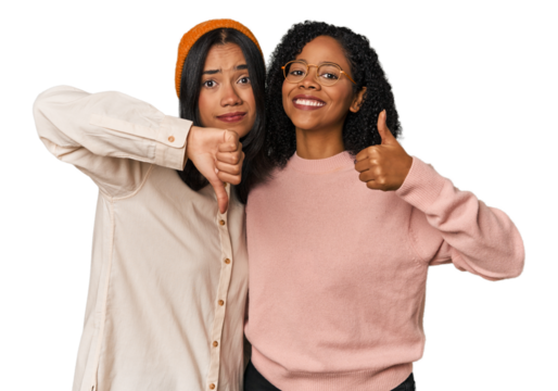 Young Latin friends together in studio showing thumbs up and thumbs down, difficult choose concept