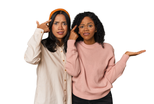 Young Latin friends together in studio holding and showing a product on hand.