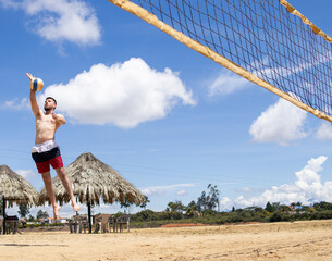 shirtless fit white man playing volleyball on a beach