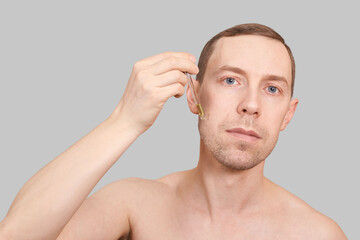 Obraz premium Man skin care routine. Oil pipette near male face. Hair serum product. Haircare facial beard treatment. Applying healthy cosmetics. Beauty skincare hydration. Isolated on grey background