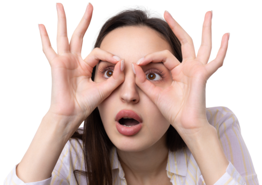 Close up portrait of attractive quirky young woman making binoculars with hands showing ok gesture on white studio background.