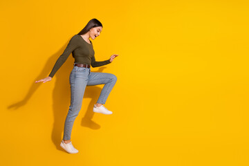 Full body photo of attractive teen woman step look empty space interested dressed stylish khaki clothes isolated on yellow color background